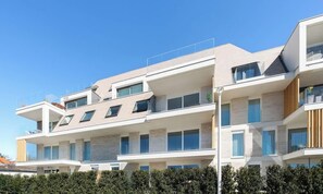 A multi-story residential building with a modern architectural design, featuring balconies, large windows, and a flat roof. - La Dolce Vickri - modern stay with garden & pool (Nieuwpoort)