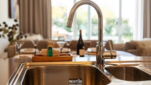 A modern kitchen with a stainless steel sink, a wooden tray with bar items, and a bottle of wine. - La Dolce Vickri - modern stay with garden & pool (Nieuwpoort)