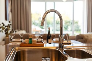 A modern kitchen with a stainless steel sink, a wooden tray with bar items, and a bottle of wine. - La Dolce Vickri - modern stay with garden & pool (Nieuwpoort)