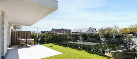 A modern house with a patio, a lawn, and a wooden fence.
