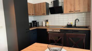 Una cocina compacta con comedor, que incluye microondas, estufa y fregadero.