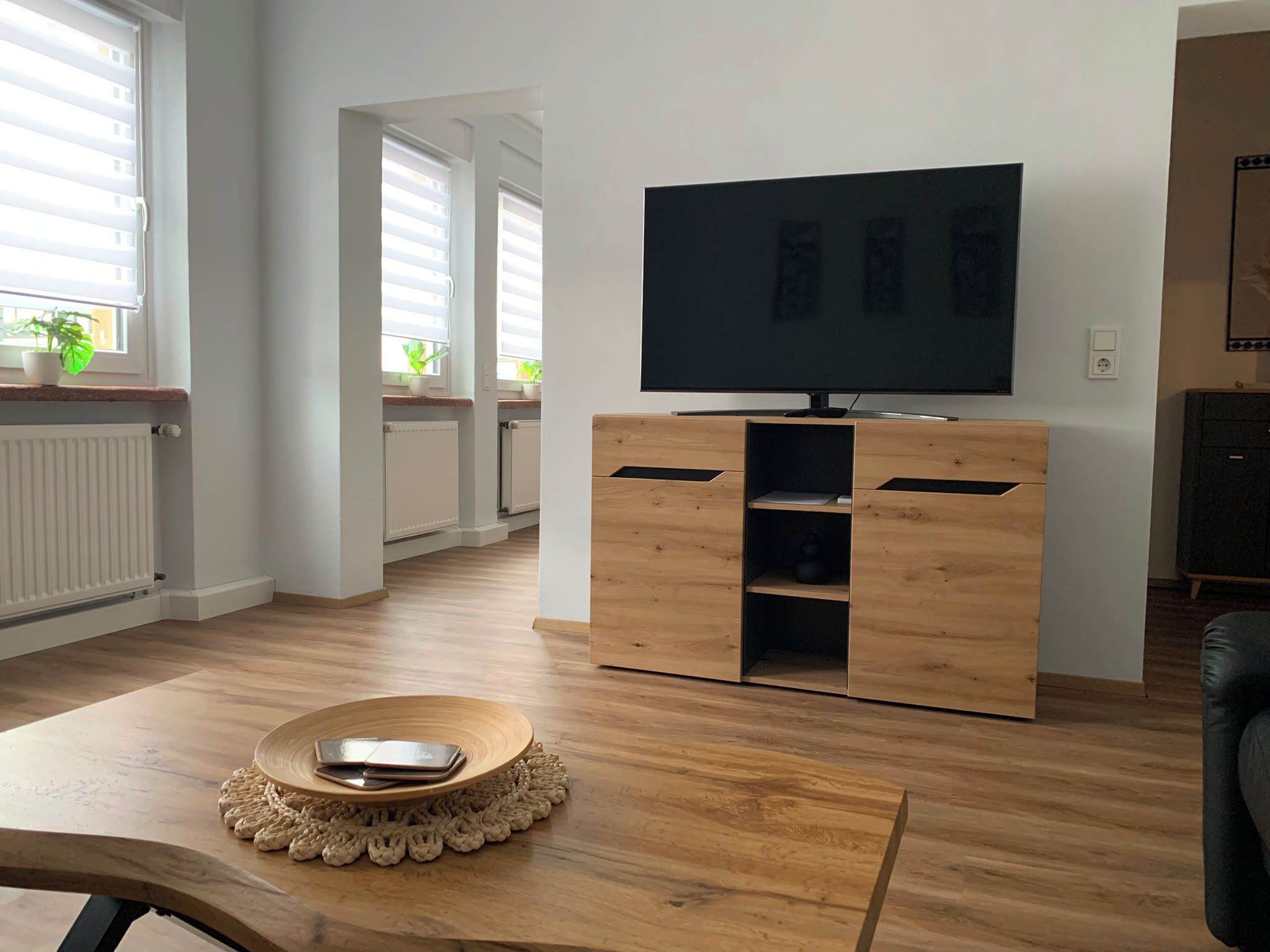 Ein modernes Wohnzimmer mit einer Holztrenneinrichtung, einem Flachbildfernseher und einem Esstisch mit Unterlage.