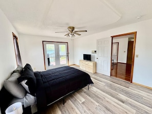 A bedroom with a bed, a ceiling fan, a TV, and a wardrobe.