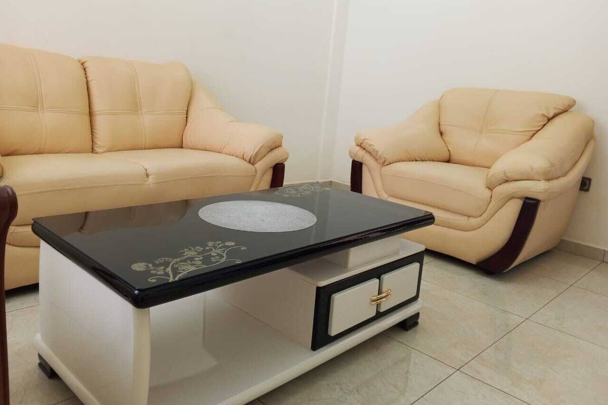 A living room with a sofa, a recliner, and a glass-top coffee table with a drawer.