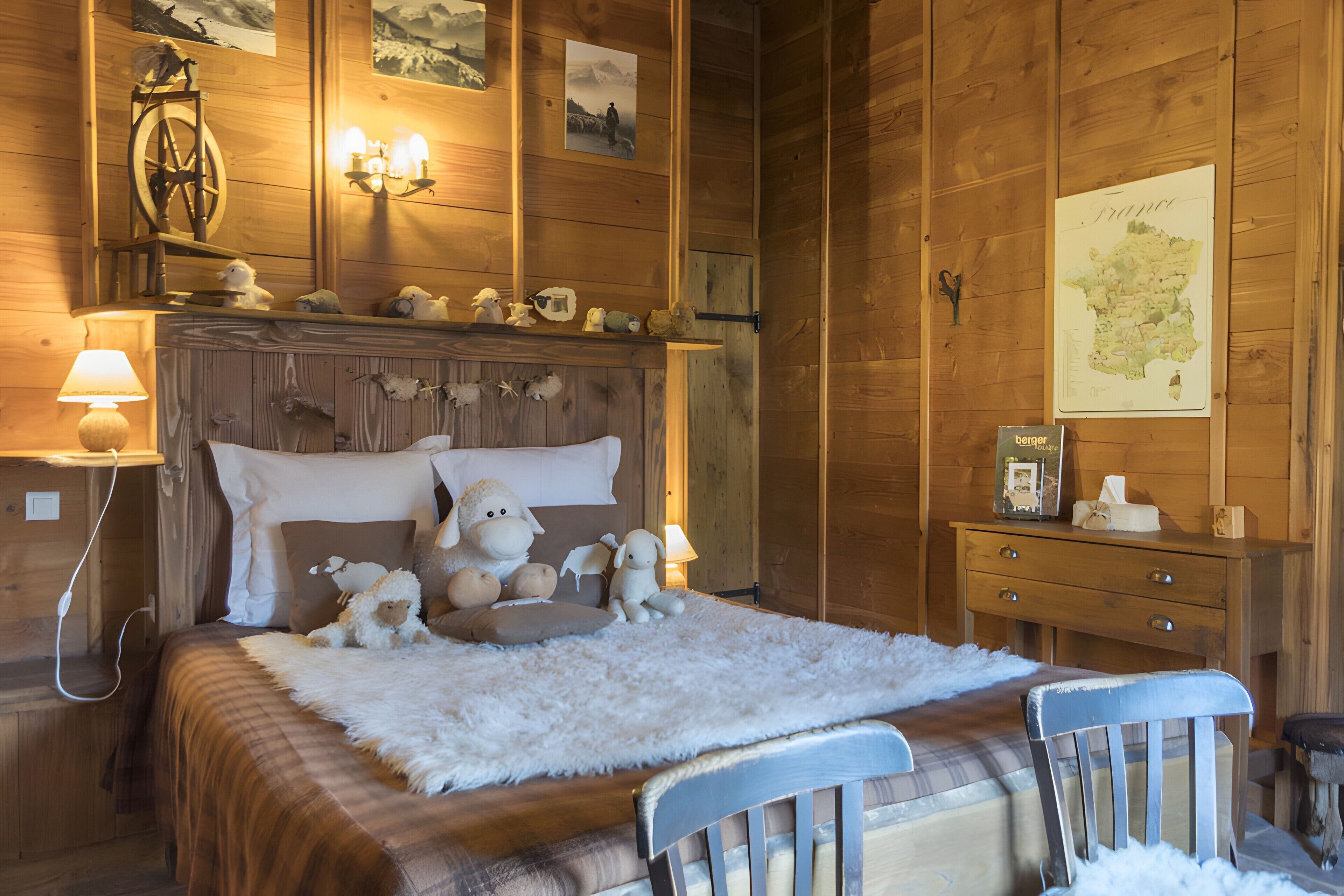 A wooden-paneled room with a bed, a dresser, and wall-mounted artwork.