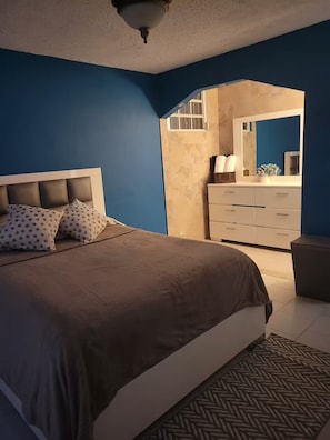 Un dormitorio con cama, cómoda y espejo.