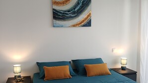 Ein Schlafzimmer mit einem Bett, zwei Nachttischen, einem Wandbild und einem Deckenventilator.