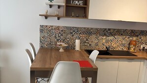 Eine moderne Küche mit einem Holztisch, weißen Stühlen, einer gefliesten Spritzschutzwand und einem Regal mit einem 'LOVE'-Schild.
