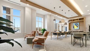 En modern hotellobby med sittgrupper, ett matbord och stora fönster.