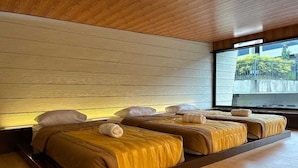 Habitación de hotel moderna con techo y suelo de madera, un ventanal grande y una cama con cabecero a juego con la pared.