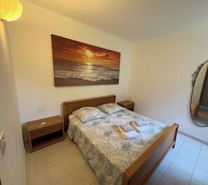 A bedroom with a bed, a nightstand, a bedside table, a wall-mounted painting, and a mirror. - Beautiful apartment in Conca, private pool and 5-minute walk to the beach (Conca)