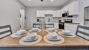 A modern kitchen with white cabinets, a microwave, and a refrigerator. - Cozy & Spacious Four Bedroom (Cleveland)
