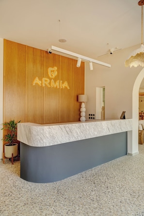 A reception desk with a wooden panel wall, a marble counter, and a tiled floor.