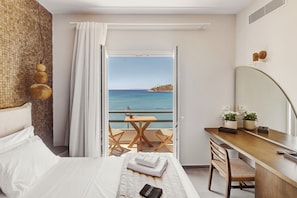 A hotel room with a bed, a desk, a chair, a small table, and a view of the sea. - Armia Experience Hotel (Syros)
