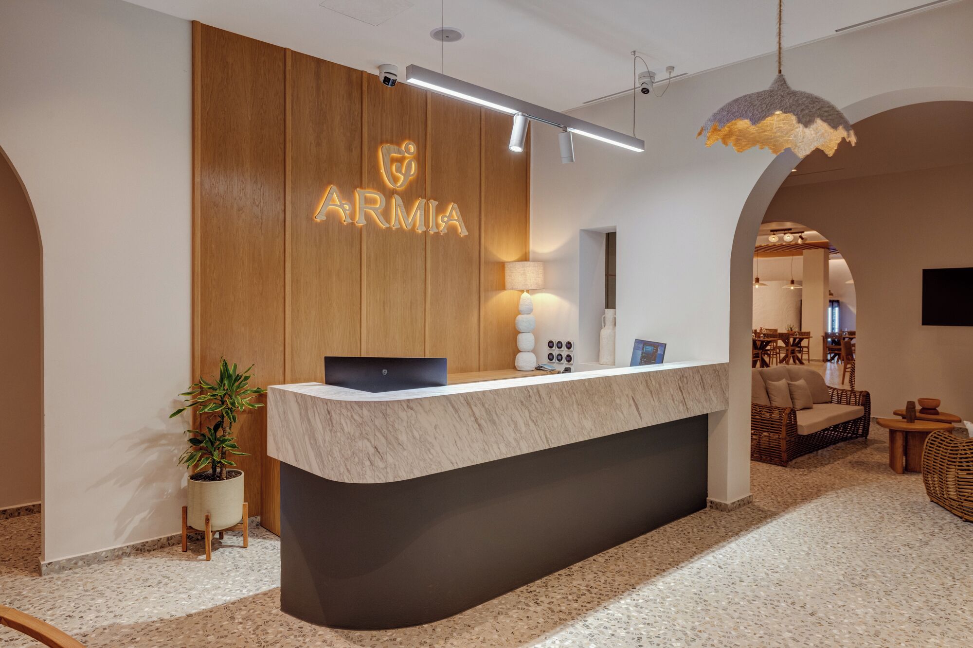 Un mostrador de recepción con un panel de madera y la palabra 'ARMIA' iluminada en el centro.
