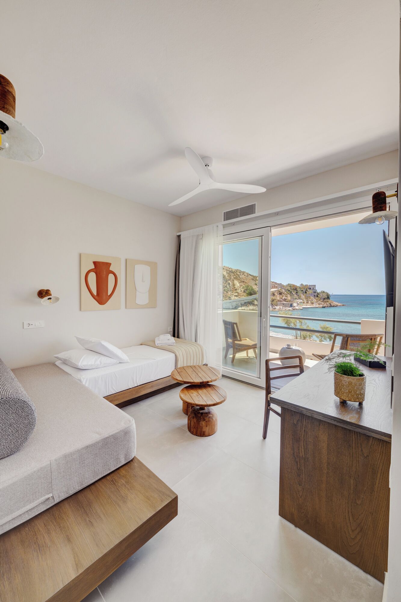 Una habitación de hotel moderna con balcón, cama, escritorio y vista al mar.