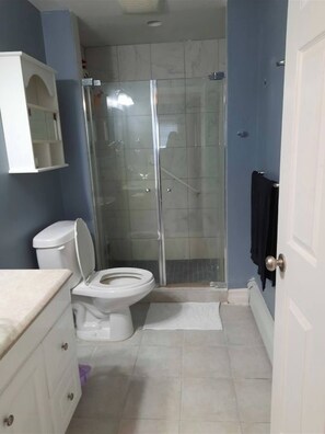 Ein Badezimmer mit Toilette, Dusche und einem weißen Schrank.