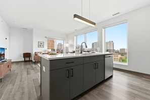Eine moderne Küche mit einer großen Kochinsel, einem Essbereich mit einer Couch und großen Fenstern mit Blick auf die Stadt.