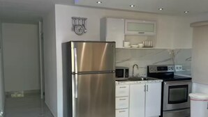 A modern kitchen with stainless steel appliances, white cabinetry, and a marble floor. - Beautiful house minutes from airport and beach (Carolina)