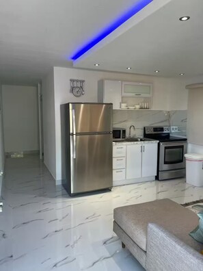 A modern kitchen with stainless steel appliances, white cabinetry, and a marble floor. - Beautiful house minutes from airport and beach (Carolina)
