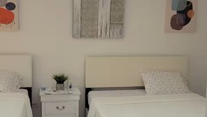 A bedroom with two beds, a nightstand, a wall-mounted artwork, and recessed ceiling lights. - Beautiful house minutes from airport and beach (Carolina)
