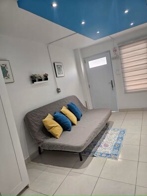 A room with a grey sofa, a patterned rug, a white door, and a blue ceiling. - Studio Beauty place (Carolina)