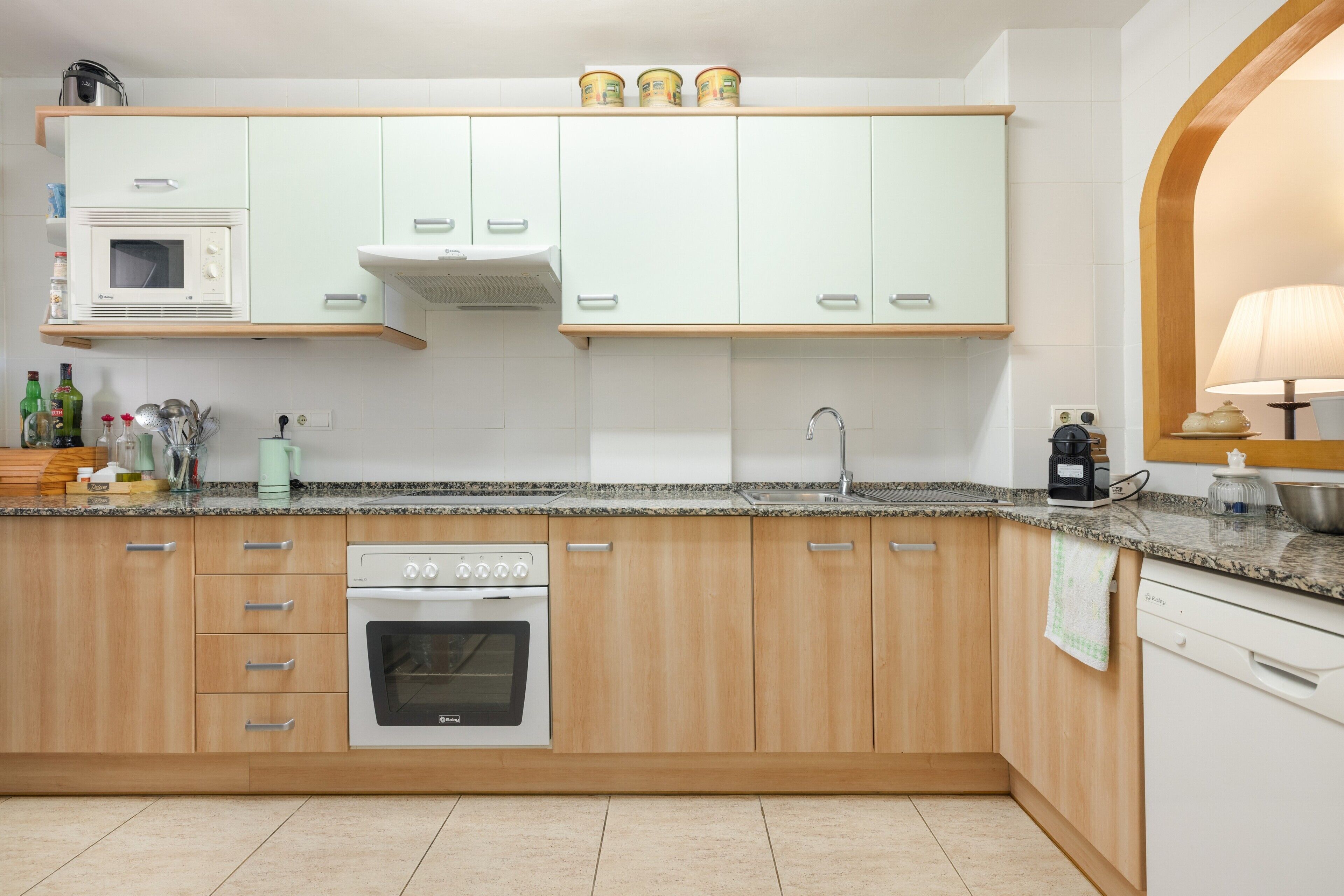Una cocina con microondas, horno, lavamanos y armarios de madera.