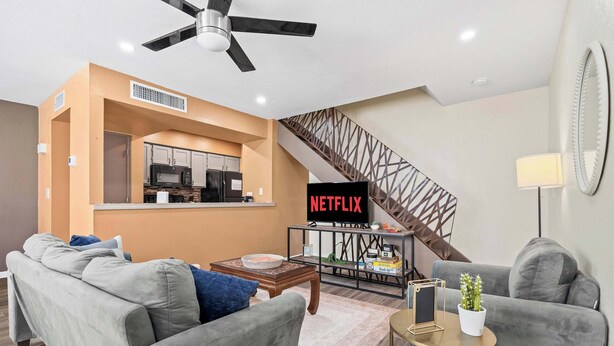 A living room with a sofa, coffee table, and a TV displaying 'NETFLIX'.