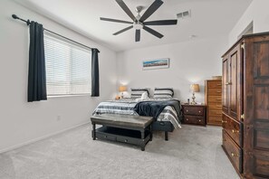 A bedroom with a bed, bedside tables, a wardrobe, a ceiling fan, and a window with curtains. - Vail Summer Desert Retreat | Colossal Cave & Parks (Vail)