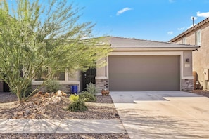 A residential house with a garage, a stone pathway, and a small garden with rocks and plants. - Vail Summer Desert Retreat | Colossal Cave & Parks (Vail)