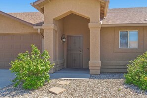 A house with a garage, a covered entryway, and a small garden area. - Southside Summer Fun Oasis | Pool, Grill & Games (Tucson)