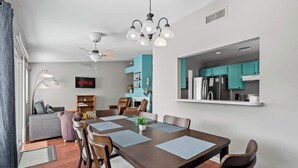 A modern dining area with a wooden table, chairs, and a ceiling fan.