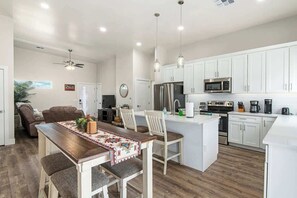 Eine moderne Küche mit weißen Schränken, einer zentralen Kochinsel und einem Essbereich mit Holztisch und Stühlen.