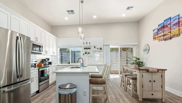 Una cocina moderna con electrodomésticos de acero inoxidable, una isla central y un comedor con mesa y sillas de madera.