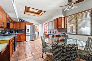 Una cocina moderna con armarios de madera, electrodomésticos de acero inoxidable y una mesa de comedor de vidrio con sillas estampadas.
