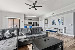 A modern living room with a grey sofa, a coffee table, and a dining area with a bench.
