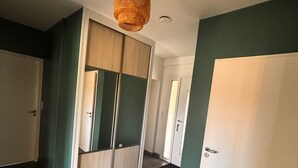 Un couloir avec une grande armoire, une porte et un luminaire suspendu.