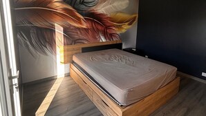 Une chambre à coucher avec un lit, une peinture murale, un luminaire au plafond et une fenêtre.