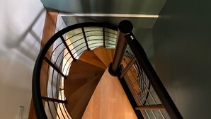 Un escalier en colimaçon avec des marches en bois et une rampe en métal.