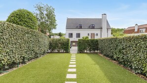 Een huis met een verzorgd gazon, een overzichtelijk pad naar de ingang en een klassieke bouwstijl.