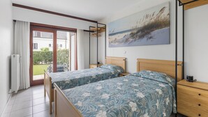 Een slaapkamer met twee bedden, een houten hoofdbord, een nachtkastje, een schilderij en uitzicht op de omgeving.