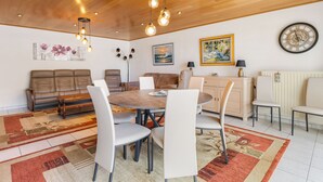Een eetruimte met een ronde tafel, stoelen en hangende lampen.