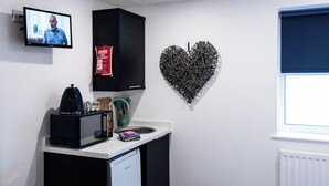 Una cocina con microondas, cafetera y una decoración de corazón en la pared.