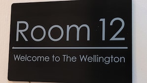 Señal que indica 'Habitación 12' y 'Bienvenido a The Wellington'.