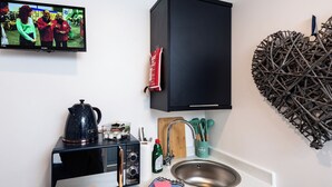 Cocina compacta con microondas, hervidor y lavabo.
