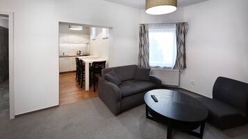A modern living room with a sofa, a coffee table, and a dining area with chairs and a table.