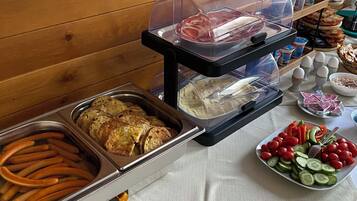 Un buffet proposant une variété de plats, notamment des viandes, des légumes et du pain, disposés sur une table avec une bouilloire.