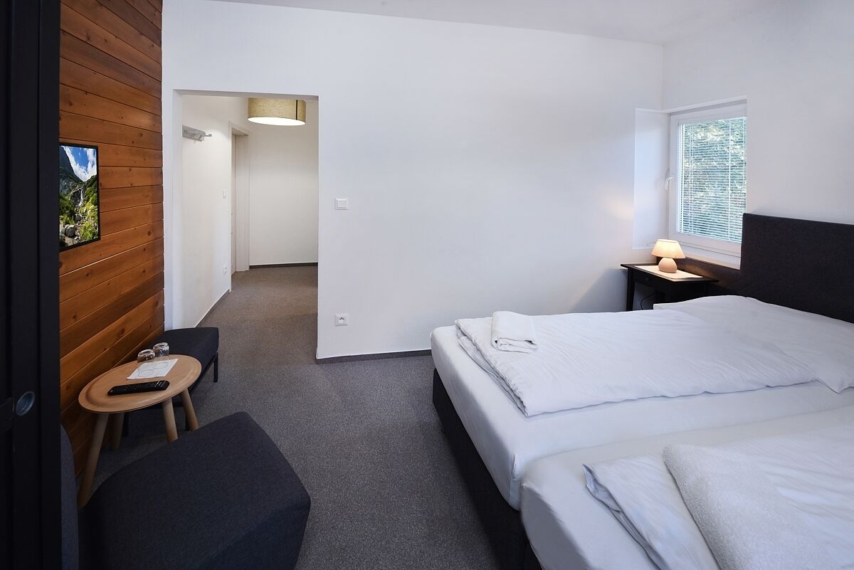 Una habitación de hotel con una cama, una mesita de noche, una lámpara y un escritorio pequeño con una silla.