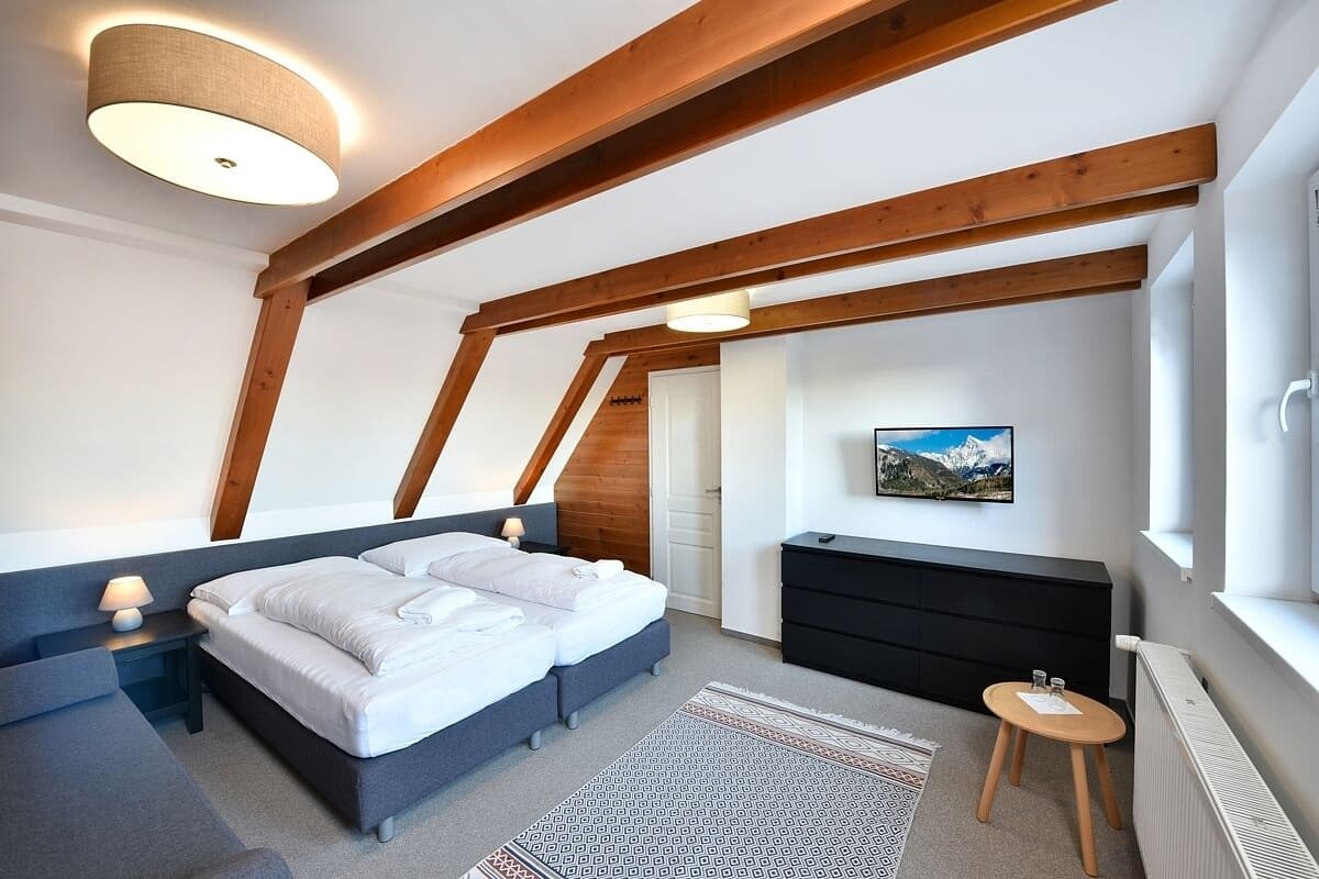 A bedroom with a bed, bedside tables, a dresser, a small stool, a rug, and a painting on the wall.