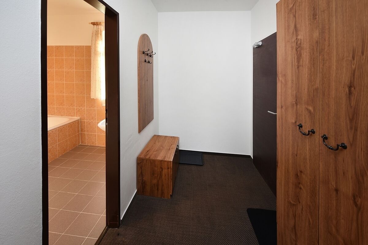 Un bagno con una panca in legno, uno specchio e una porta con maniglia.